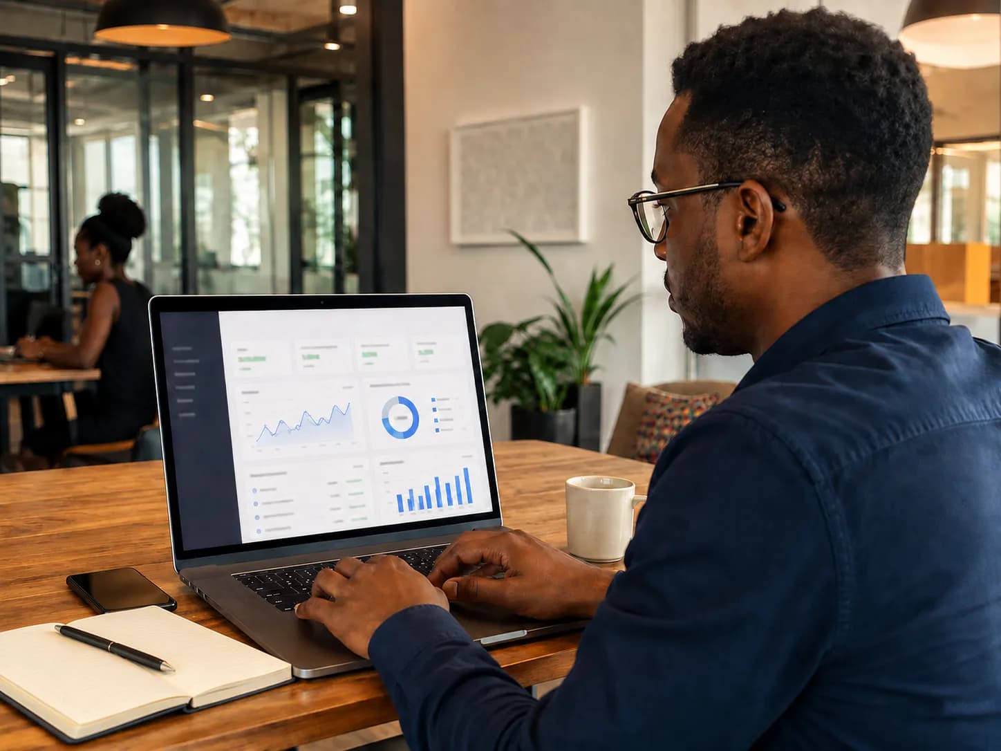 A software team member reviewing account activity on a laptop at a shared office desk.